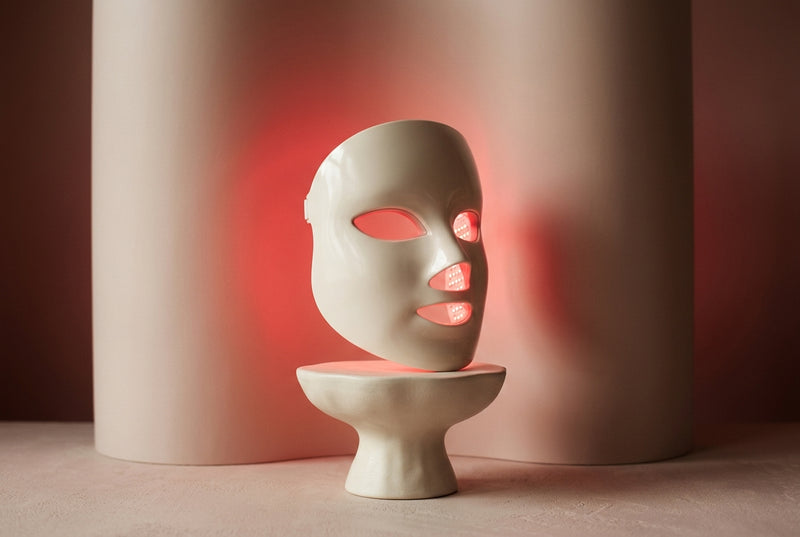 Rubralight LED face mask on a pedestal with a soft red glow